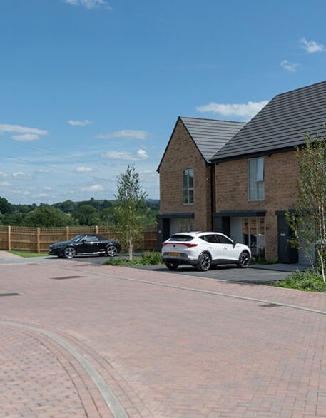 An external shot of Keld homes with two cars on the large driveway.