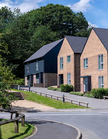 An external shot of Keld, a Northstone development, with 4 houses side by side in beside some greenery.